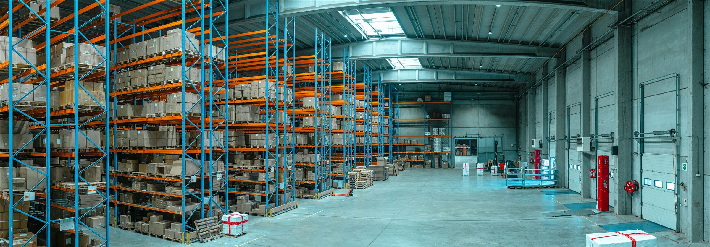 Interior de un depósito con estanterías de mercadería y muelles de carga